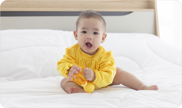 Baby in yellow outfit on a bed